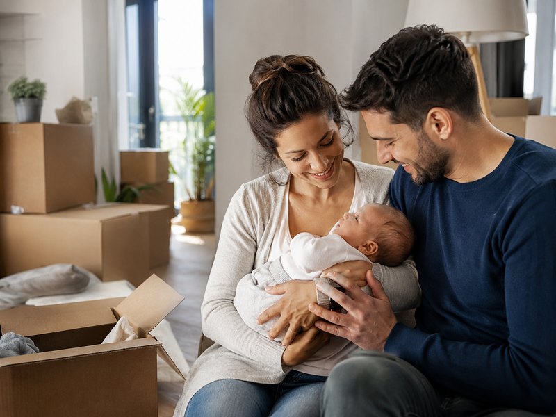New parents holding their newborn baby amid moving boxes