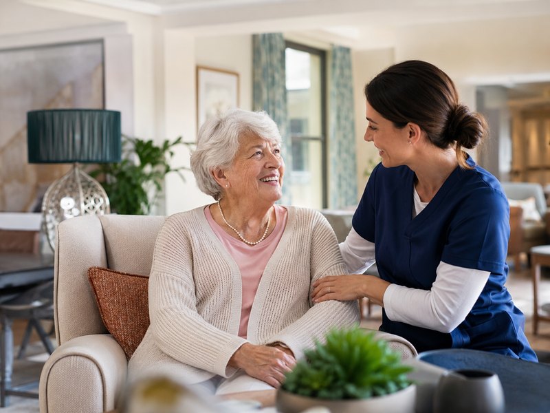 A caregiver visiting with a resident in a warm, modern care setting